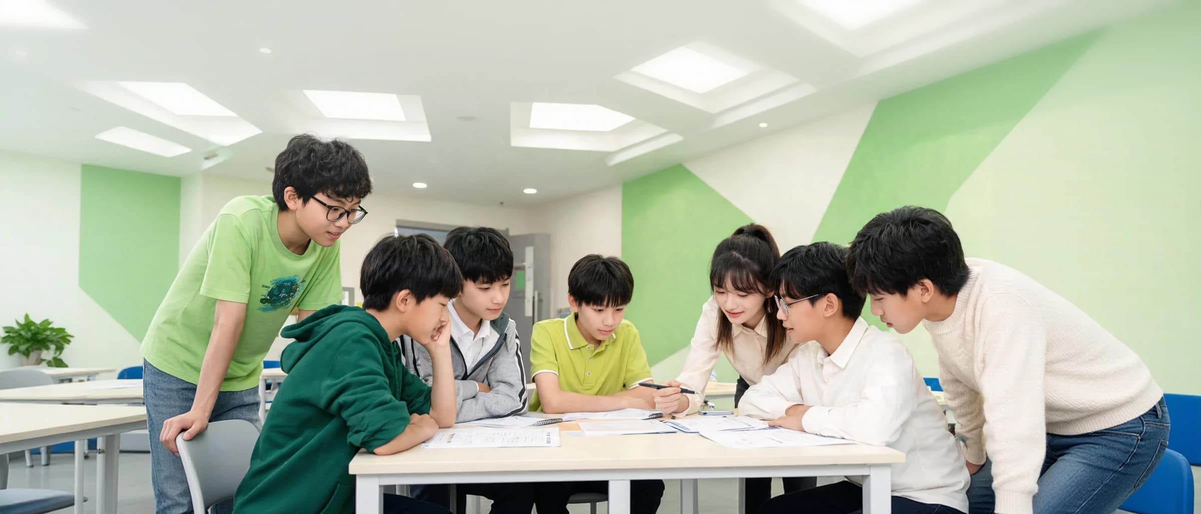 老师与六位学生在明亮的精品小班课堂中围桌研讨